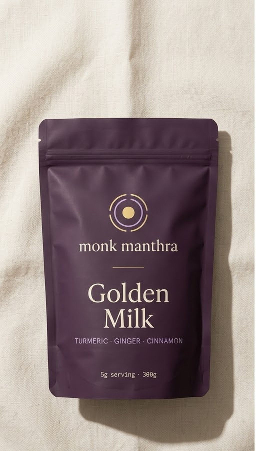 Golden Milk — turmeric, ginger and cinnamon, matte purple pouch photographed overhead on linen